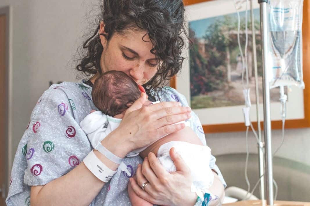 A NICU mom holding her baby after not visiting baby in the NICU.